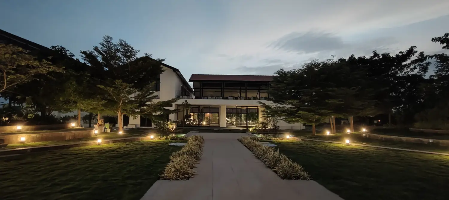Eden 144 at dusk — the lit entrance avenue of the delivered community